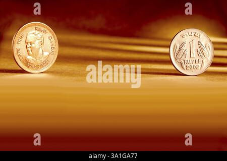 Doppeltes Paar indische Währung eine Rupie Münze Vorder- und Rückseite Weise geprägt Rajiv Gandhi 1944-1991 auf orangem Hintergrund Stockfoto