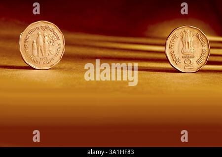 Zwei Paar indische Währung zwei Rupien Münze Vorder- und Rückseite Art geprägt kleine glückliche Familie 1993 auf orangem Hintergrund Stockfoto