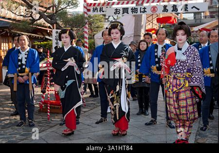 Zwei Filmschauspieler, die als Kyoto Geiko (Geisha) gekleidet sind, zusammen mit anderen Schauspielern aus der Zeit des Uzumasa Toei Studios bei einer Veranstaltung im Ebisu Jinja in Kyoto, Japan. Stockfoto