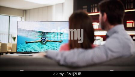 Ein Paar, das sich auf dem Sofa entspannt und zu Hause fernsieht. Stockfoto