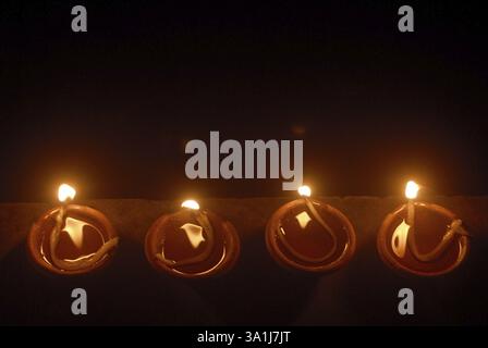 Aus der Vogelperspektive vier kleine, mit Öl gefüllte, erdgrüne Gefäße, die zur Feier des Gudi Padva Festivals, Neujahr der hinduistischen Religion, Masunda, beleuchtet sind Stockfoto