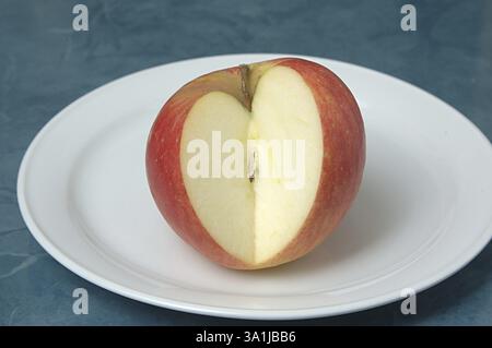 Essensfrucht, roter Apfel in Herzform auf einem weißen Teller geschnitten Stockfoto