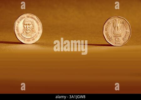 Doppelpaar indische Währung zwei Rupien Münze Vorder- und Rückseite Weise geprägt Sri Aurbindo All Life is Yoga 1998 auf orangem Hintergrund Stockfoto