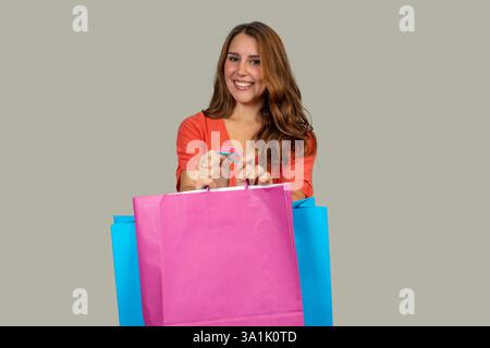 Glücklicher Käufer, der bunte Einkaufstaschen auf grauem Hintergrund hält Stockfoto