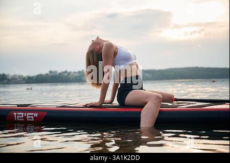 Sitzen und entspannen. Die junge Frau ist auf den Brettern im See. Stockfoto