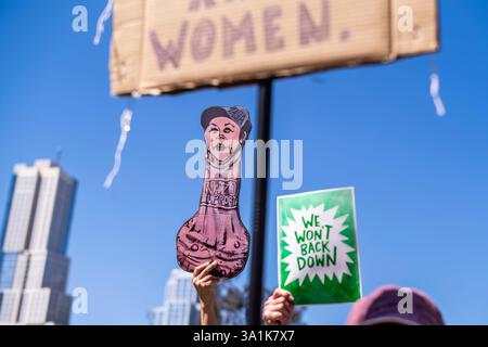 Los Angeles, Usa. März 2025. Die Demonstranten halten Plakate, die ihre Meinung zum Ausdruck bringen, während sie zum Frauenmarsch in Los Angeles auf den Straßen der Innenstadt von Los Angeles fahren. Quelle: SOPA Images Limited/Alamy Live News Stockfoto