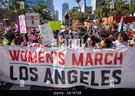 Los Angeles, Usa. März 2025. Die Demonstranten halten Plakate und ein Banner, während sie zum Frauenmarsch in Los Angeles auf die Straßen der Innenstadt von Los Angeles gehen. Quelle: SOPA Images Limited/Alamy Live News Stockfoto