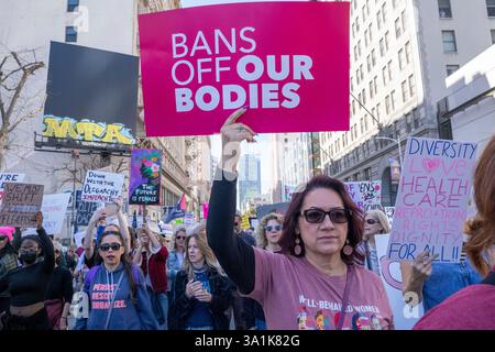 Los Angeles, Usa. März 2025. Die Demonstranten halten Plakate, die ihre Meinung zum Ausdruck bringen, während sie zum Frauenmarsch in Los Angeles auf den Straßen der Innenstadt von Los Angeles fahren. Quelle: SOPA Images Limited/Alamy Live News Stockfoto