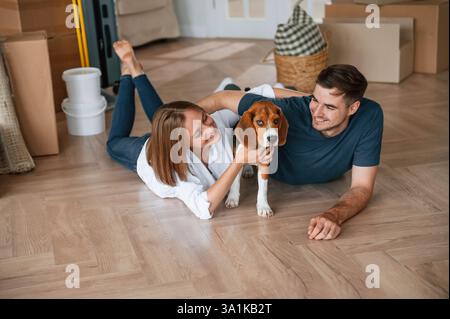 Mit Hund spielen. Das junge Paar zieht in ein neues Zuhause. Stockfoto