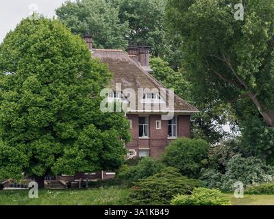 Charmantes Country Brick House umgeben von üppigen grünen Bäumen und Büschen Stockfoto