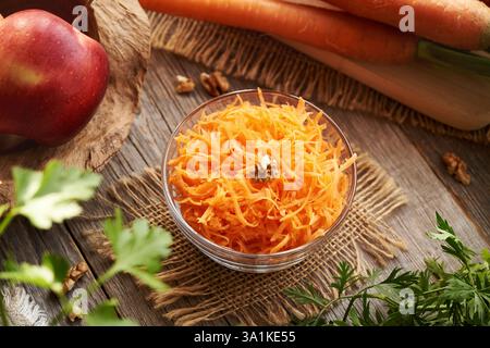 Karottensalat auf einem Tisch mit frischen roten Äpfeln Stockfoto