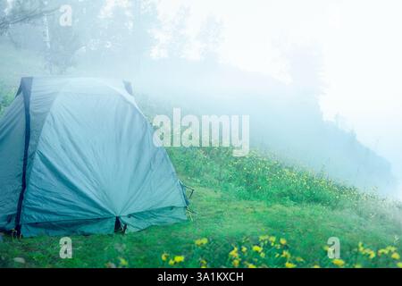 Ein abgelegenes Campingzelt auf einem Berg an einem abgeschiedenen Ort im Wald während des Morgennebels im Sommer. Ein friedlicher und ruhiger Campingplatz Stockfoto