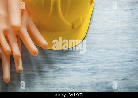 Paar Gummiisolierhandschuhe, die einen Helm auf Holzbrett bauen, Elektrizitätskonzept Stockfoto