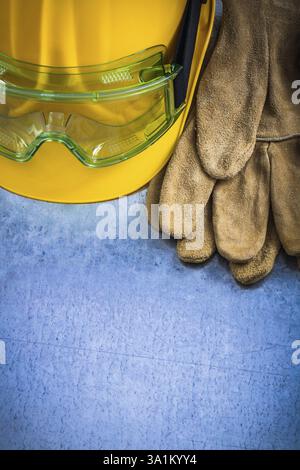 Ein Paar Schutzhandschuhe aus Leder, Schutzhelm und Schutzbrille auf einem zerkratzten metallischen Hintergrund Stockfoto