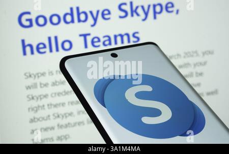 Das Skype-Logo wird auf einem Smartphone-Bildschirm angezeigt. Die skype-Startseite zeigt im Hintergrund auf einem Computerbildschirm „Goodbye Skype, Hallo Teams“ an Stockfoto