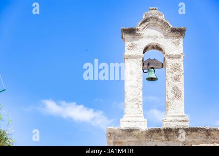Weißer Glockenturm mit grüner Glocke mit Blick auf den blauen Himmel von Polignano a Mare in Apulien, Süditalien, mit einer einfachen, aber eleganten Architektur Stockfoto