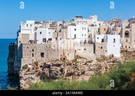 Weiße Häuser von Polignano a Mare stehen an einem sonnigen Sommertag in Apulien auf einer Klippe mit Blick auf die Adria Stockfoto