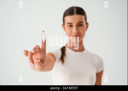 Die junge Frau steht mit Creme für das Gesicht. Im Studio. Stockfoto