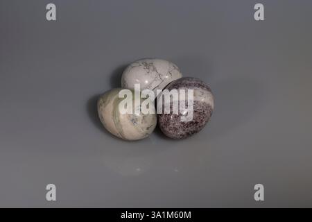 Eine Stillebenskupplung aus drei Steineiern in verschiedenen Farben mit weißem Hintergrund. Ein traditionelles Symbol des christlichen Osterfestes. Stockfoto