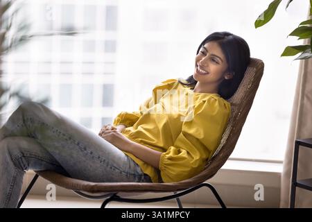 Frau, die sich einen Moment Zeit nimmt, um sich in einem modernen Sessel zu entspannen Stockfoto