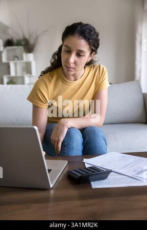 Ernsthafte junge Frau überprüft zu Hause Finanzdokumente Stockfoto