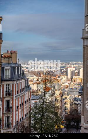 Blick auf Paris mit Haussmann-Gebäuden, Dächern und fernen Skyline unter blauem und bewölktem Himmel Stockfoto