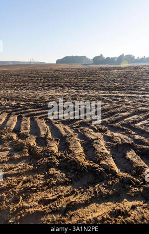 Spuren von rauer Lauffläche von Automobilrädern auf dem gepflügten Boden des Feldes, Spuren von Zugmaschinen und anderen landwirtschaftlichen Maschinen auf dem Boden im Boden Stockfoto