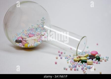 Bunte Pillen verschüttet aus umgedrehten Florenz Flasche mit hohem schmalen Hals Stockfoto