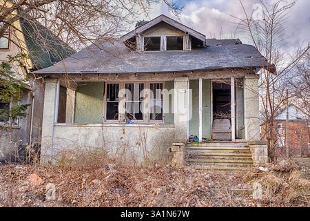 Ein kaputtes Haus mit kaputten Fenstern und einem alten Sessel in der leeren Tür in Detroit, Michigan. Stockfoto