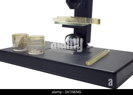 Monokulares Mikroskop mit Pinzette auf Objektträgern und Tropfer- und Glasgläsern für Proben auf dem Instrumententisch. Verstellbarer, ebener Spiegel für Fahrlicht, Stockfoto