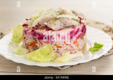 Mehrschichtiger Gemüsesalat mit Rüben und Hering auf einem Holztisch. Stockfoto