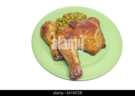 Im Ofen gebratene Hähnchenschenkelviertel, mit grünen Erbsen aus der Dose, auf großer grüner Platte. Isoliert auf weißem Hintergrund Stockfoto