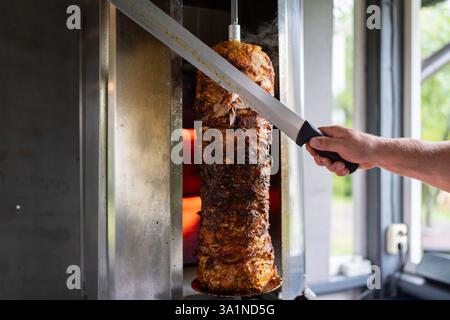 Der Koch bereitet traditionelles türkisches Dönerfleisch zu. Gegrilltes Fleisch für die Herstellung eines traditionellen türkischen Essens Döner Kebab oder griechischer Gyros. Stockfoto