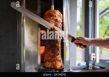 Der Koch bereitet traditionelles türkisches Dönerfleisch zu. Gegrilltes Fleisch für die Herstellung eines traditionellen türkischen Essens Döner Kebab oder griechischer Gyros. Stockfoto