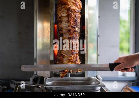 Der Koch bereitet traditionelles türkisches Dönerfleisch zu. Gegrilltes Fleisch für die Herstellung eines traditionellen türkischen Essens Döner Kebab oder griechischer Gyros. Stockfoto
