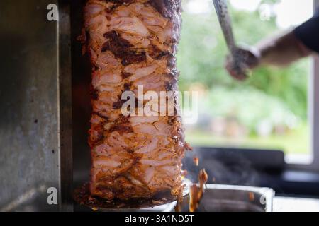 Der Koch bereitet traditionelles türkisches Dönerfleisch zu. Gegrilltes Fleisch für die Herstellung eines traditionellen türkischen Essens Döner Kebab oder griechischer Gyros. Stockfoto