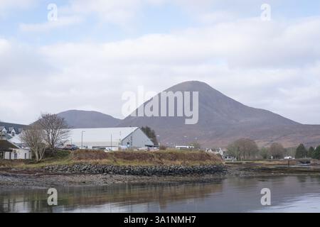 Blick von der Broadford Slipway auf Skye, Schottland, auf die Rückseite des Co-op Supermarktes mit seinem Parkplatz. Beinn na Caillich ist dahinter zu sehen. Stockfoto