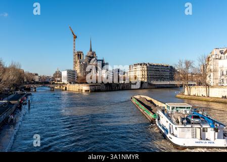 Ein Lastkahn auf der seine mit im Hintergrund der Rückseite der Notre Dame de Paris an einem sonnigen Wintertag. Stockfoto