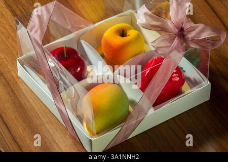 Geschenkset Mousse-Kuchen in Form von Früchten und Beeren in einer Box. Karton mit Kuchen in Form von Mango, Pfirsich, Kirsche und Erdbeere Stockfoto