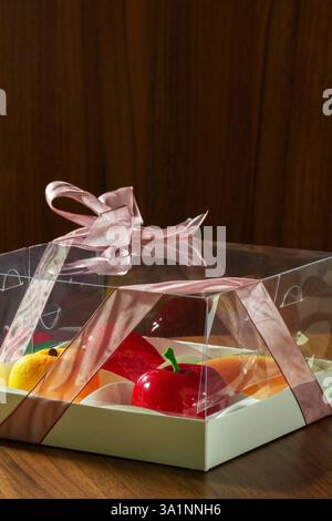 Geschenkset Mousse-Kuchen in Form von Früchten und Beeren in einer Box. Karton mit Kuchen in Form von Mango, Pfirsich, Kirsche und Erdbeere Stockfoto