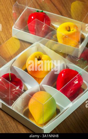 Geschenkset Mousse-Kuchen in Form von Früchten und Beeren in einer Box. Karton mit Kuchen in Form von Mango, Pfirsich, Kirsche und Erdbeere Stockfoto