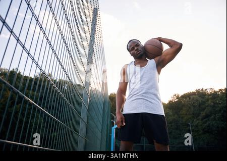 Ansicht von unten. Der junge Schwarze ist draußen mit Basketball. Stockfoto