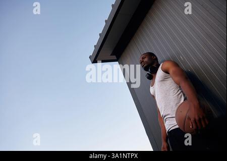 Ansicht von unten. Der junge Schwarze ist draußen mit Basketball. Stockfoto