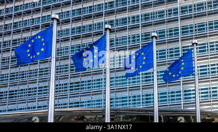 Europäische Fahnen, Symbole der Europäischen Union (EU), flattern gegen das Berlaymont-Gebäude, Sitz der Europäischen Kommission in Brüssel Stockfoto