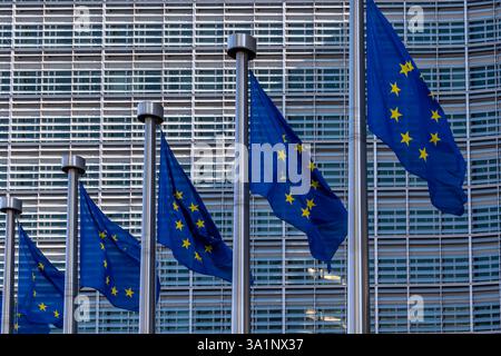 Europäische Fahnen, Symbole der Europäischen Union, flattern gegen das Berlaymont-Gebäude, Sitz der Europäischen Kommission in Brüssel Stockfoto