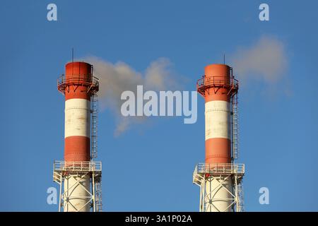 Rauchende Pfeifen auf klarem Himmel Hintergrund. Konzept der Dampfanlage, Luftverschmutzung, Heizsaison oder Fabrikschornstein Stockfoto