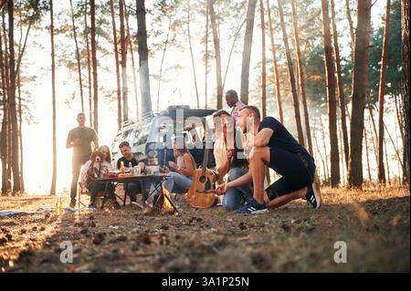 Ein Paar sitzt am Lagerfeuer. Eine Gruppe von Freunden ist zusammen im Wald. Stockfoto