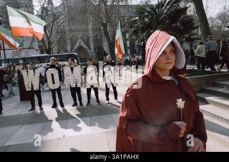 Handmaids Tale Protest in London am Internationalen Frauentag, 8. März 2024, marschierten britisch-iranische Frauen, organisiert von der Gruppe Stage of Freedom, schweigend durch das Zentrum Londons, gekleidet in roten Mänteln und weißen Hauben, die an die Handmaids Tale erinnern. Die Prozession begann am Parlamentsplatz und endete in der iranischen Botschaft in Kensington. Die Teilnehmer trugen Plakate von Demonstrantinnen, die seit Beginn der Mahsa-Proteste im September 2022 vom iranischen Regime getötet, verletzt oder inhaftiert worden waren, ausgelöst durch den Tod der 22-jährigen Mahsa Amini während der Haft der Irans Mora Stockfoto