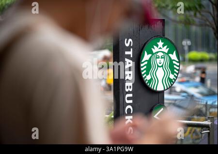 China. August 2024. Ein Mann benutzt sein Handy als das amerikanische Starbucks Coffee Logo und Geschäft im Hinterhof in Shenzhen, China. (Credit Image: © Sebastian ng/SOPA images via ZUMA Press Wire) NUR REDAKTIONELLE VERWENDUNG! Nicht für kommerzielle ZWECKE! Stockfoto