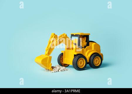 Das gelbe Mini-Bagger-Spielzeug gräbt Steinschutt aus Stockfoto